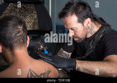 tattooist making a tattoo on a client's arm Stock Photo