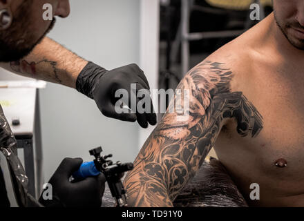 tattooist making a tattoo on a client's arm Stock Photo