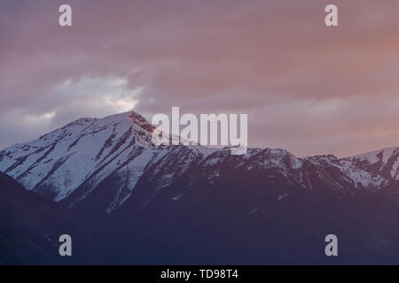 Snowy mountain and stormy sunset sky Stock Photo