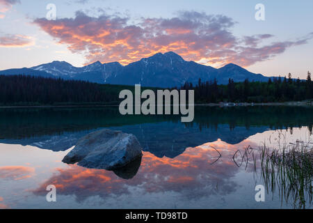 Still lake and mountain at sunset, with red clouds in sky Stock Photo