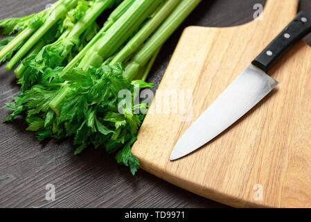 Bunch of fresh celery stalk on wooden table and cutting board and knife with leaves. Food and ingredients  of healthy vegetable. Freshness herbal and  Stock Photo