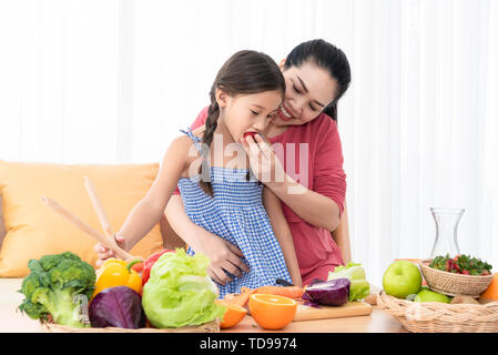 Mother and daughter cooking and eating homemade food together at home. People lifestyles and food ingredients. Health and nutrition concept. Stock Photo