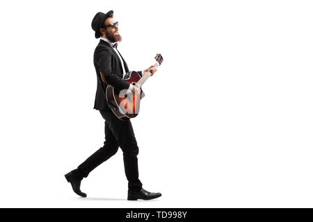 Full length profile shot of a male musician walking and playing an acoustic guitar isolated on white background Stock Photo