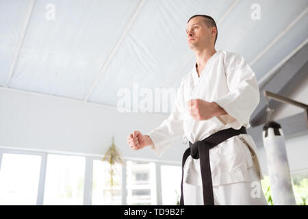 Experienced aikido master. Young but experienced aikido master wearing kimono showing his fists Stock Photo