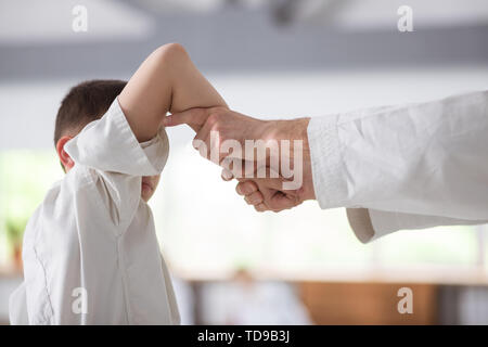 Aikido time. Close up of boy and his trainer wearing white kimono and doing aikido Stock Photo