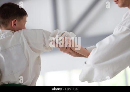 Preparing for competition. Dark-haired active boy preparing for aikido competition with trainer Stock Photo