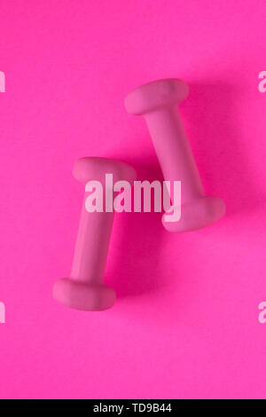 Fitness equipment with womens pink weights/ dumbbells isolated on a pink background with copyspace (aka empty text space). Stock Photo