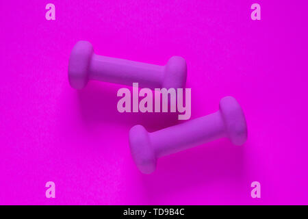 Fitness equipment with womens purple weights/ dumbbells isolated on a purple background with copyspace (aka empty text space). Stock Photo