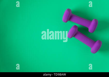Fitness equipment with womens purple weights/ dumbbells isolated on a teal green background with copyspace (aka empty text space). Stock Photo