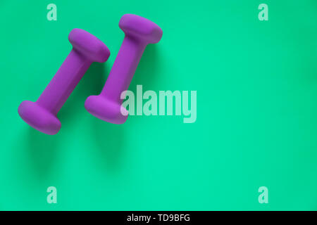 Fitness equipment with womens purple weights/ dumbbells isolated on a teal green background with copyspace (aka empty text space). Stock Photo