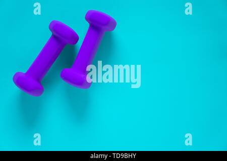 Fitness equipment with womens purple weights/ dumbbells isolated on a light sky blue background with copyspace (aka empty text space). Stock Photo