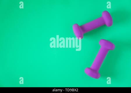 Fitness equipment with womens purple weights/ dumbbells isolated on a teal green background with copyspace (aka empty text space). Stock Photo