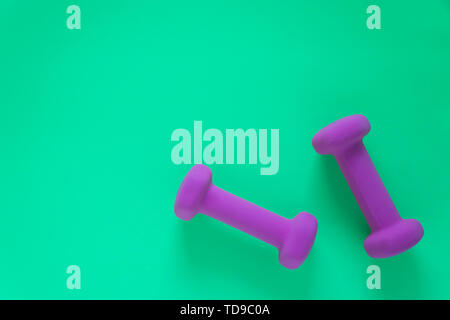 Fitness equipment with womens purple weights/ dumbbells isolated on a teal green background with copyspace (aka empty text space). Stock Photo