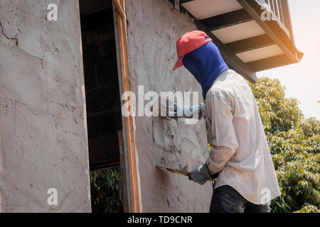 Construction workers plastering building wall using cement plaster Stock Photo
