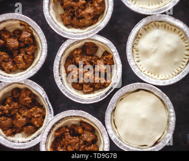 raw closed mini-quiche quiche stuffed with meat and mushrooms, on a dark background. view from above. Stock Photo