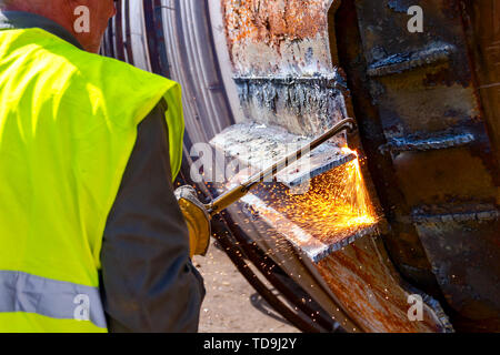 Worker is cutting manually old metal construction using gas mixture of oxygen and acetylene, propane. Stock Photo