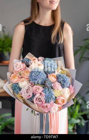 Beautiful bouquet of mixed flowers in woman hand. Floral shop concept . Handsome fresh bouquet. Flowers delivery. Blue and pink color Stock Photo