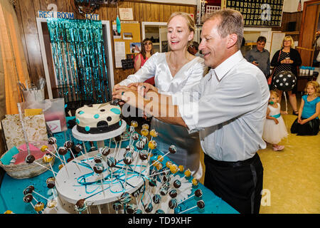 Bride & groom cut the cake at wedding reception;  Congressional Church; Buena Vista; Colorado; USA Stock Photo