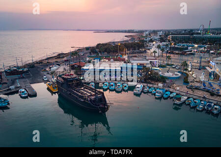 A lot of ships are in the port near the shore on the background of a beautiful sunset. Mediterranean coast of Cyprus, Ayia NAPA. Stock Photo