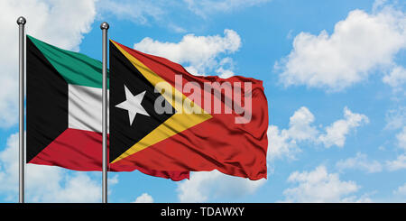 East Timor and Kuwait flag waving in the wind against white cloudy blue ...