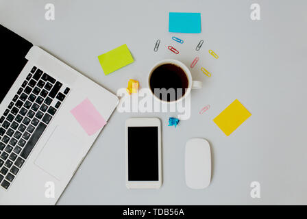 Flatlay composition with laptop keyboard, cup of hot black coffee, white smartphone and computer mouse on light grey background. Copy space. Stock Photo