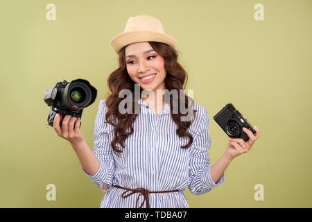 Young woman comparing professional and compact cameras on a solid background Stock Photo