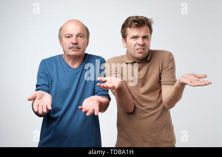 father and son raise hands as shows being confused Stock Photo