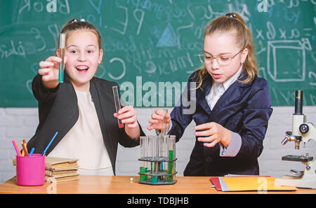Be careful performing chemical reaction. Basic knowledge of chemistry. Girls study chemistry. Make studying chemistry interesting. Educational experiment concept. Microscope and test tubes on table. Stock Photo