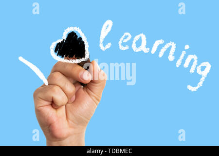 Closeup of man colouring heart symbol with black marker in i love learning text on transparent display isolated on white backgroud Stock Photo