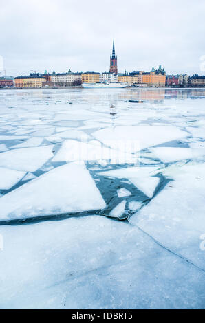 Winter view of Stockholm Old Town, Gamla Stan and Riddarholm church, with boats moored in the frozen lake leading to the Baltic Sea. Stock Photo