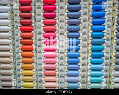 Colorful sewing threads on display in shop from dark to light Stock Photo