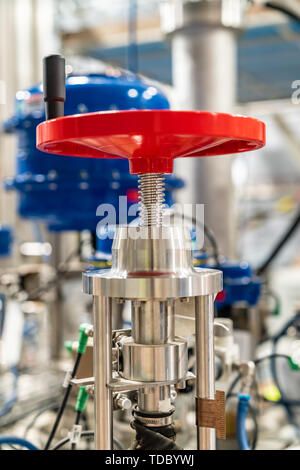 Red manual hand valve in a in a large industrial plant Stock Photo