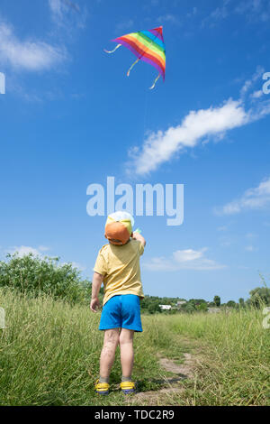 little boy launches colorful kite in the blue sky Stock Photo