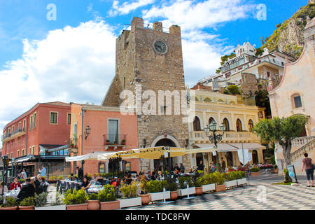 Taormina, Sicily, Italy - Apr 8th 2019: People sitting in outdoor restaurants and cafes on beautiful Piazza IX Aprile square in front famous Clock Stock Photo