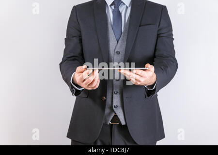 Handsome young man looking on tablet on white background. Male model in business suit looking at copyspace Stock Photo
