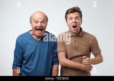 Two astonished men keeping mouths opened, shouting in shock Stock Photo