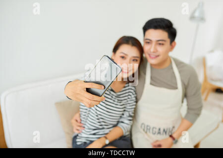 Happy Asian Lover sitting and using the digital technology tablet to selfie over the sofa of living room at modern home, Couple successfull and lifest Stock Photo