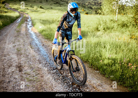 Professional well-equipped cyclist riding on the mountain road during the sunset Stock Photo