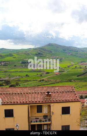 Vertical photo capturing amazing Sicilian landscape with houses in village Gangi in Italy. Cloudy day. Green hilly countryside. Popular tourist destination. Stock Photo