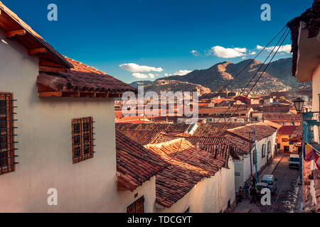 Cusco / Peru - May 27.2008: View on the narrow city street between the houses in downtown during sunset. Local architecture. Stock Photo