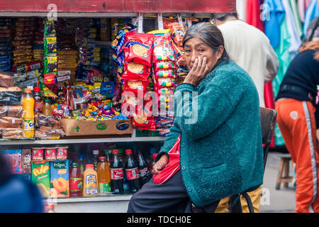 Lima / Peru Jun 13.2008: Old indigenous woman seating next to the colorful Newsstand on the street of the biggest garment district called Gamarra. Stock Photo