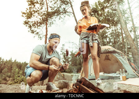 Nice young couple grilling food together on fire Stock Photo