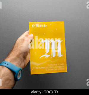 Paris, France - Oct 30, 2017: Man hand holding yellow Le Monde Christmas gift catalog from the publishing house in France Stock Photo