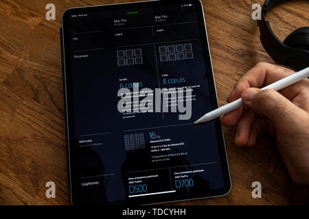 Paris, France - Jun 6, 2019: Man reading on Apple iPad Pro tablet about powerful professional workstation computer Mac Pro with compare table with technical specification between machines Stock Photo