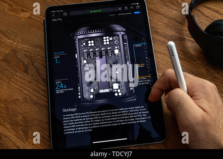Paris, France - Jun 6, 2019: Man reading on Apple iPad Pro tablet about powerful professional workstation computer Mac Pro with SSD PCIe, hard disk drive Stock Photo