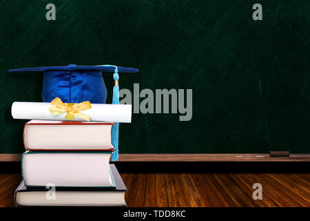 Education concept with blue graduation hat and diploma on stack of books on blackboard background. Copy space on chalk board. Stock Photo