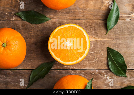 Fresh oranges and leaves on wooden board background Stock Photo