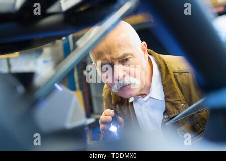 mechanic using torch to inspect vehicle Stock Photo