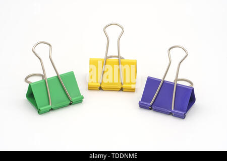 Three stationery clips yellow, green and purple on a white background. Clothespins for papers. Office. Stationery Stock Photo