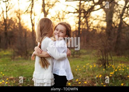 Best friends happy to meet you. Girls in white dresses cuddling in spring meadow. Family bonds Stock Photo